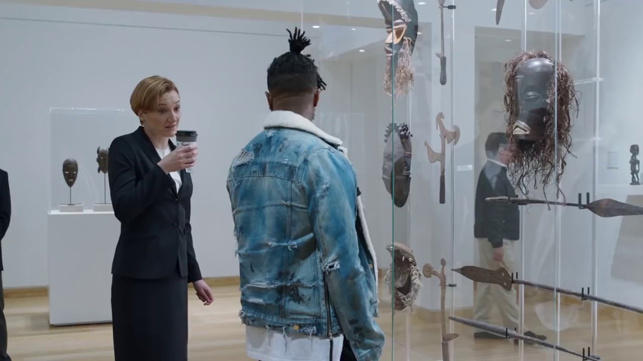 Descriptive visual from Black Panther movie, Killmonger looking at Stolen African art in British museum